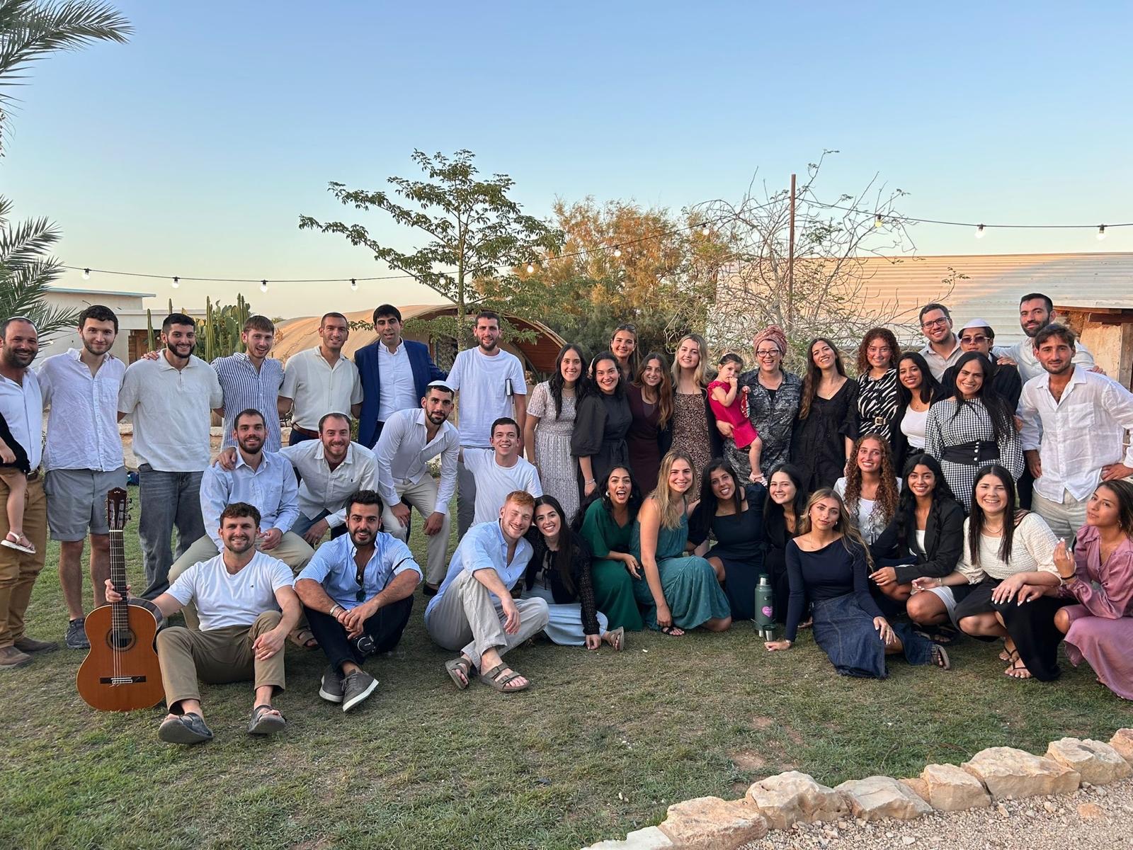 The La Casa TLV community gathered in a garden at sunset under string lights